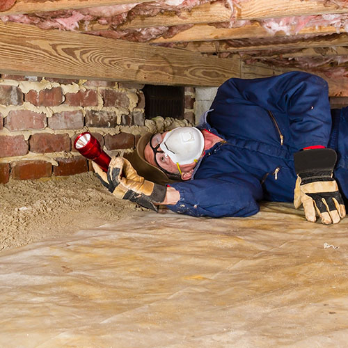 A building inspector checking underneath a house.